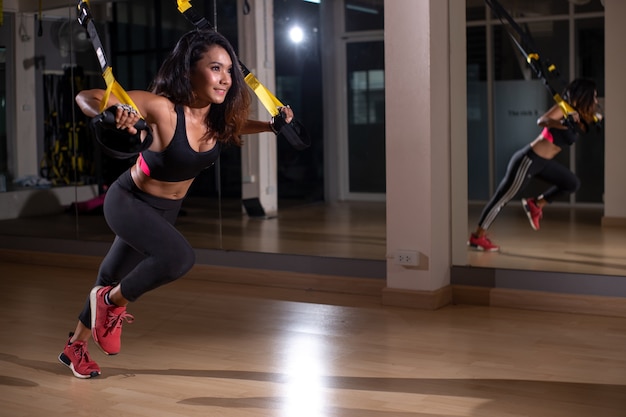 Starke Frau, die trx Übung mit Bügeln in der Eignungsturnhalle tut