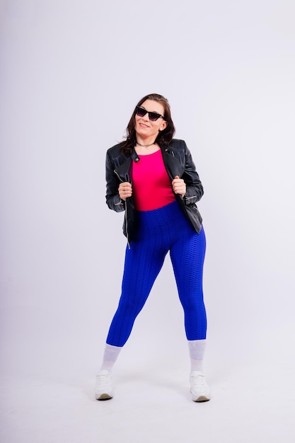 Starke Frau zeigt ihre Bizeps in modischer Sportkleidung im Studio-Hintergrund Stärke und Motivation