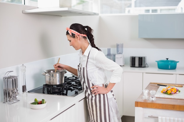 Starke hübsche Frau mit dem Schutzblechkochen