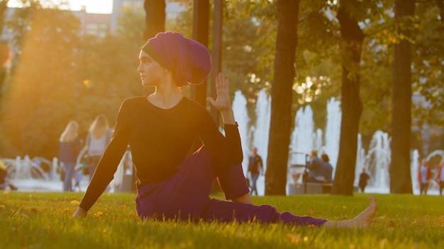 Starke islamische muslimische indische Frau im Hijab aktives Mädchen, das Yoga im Park im Freien trainiert