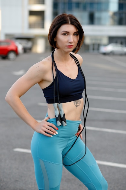 Starke junge Frau, die mit dem Überspringen ausdehnt. Fitness-Athletin, die im Freien trainiert.