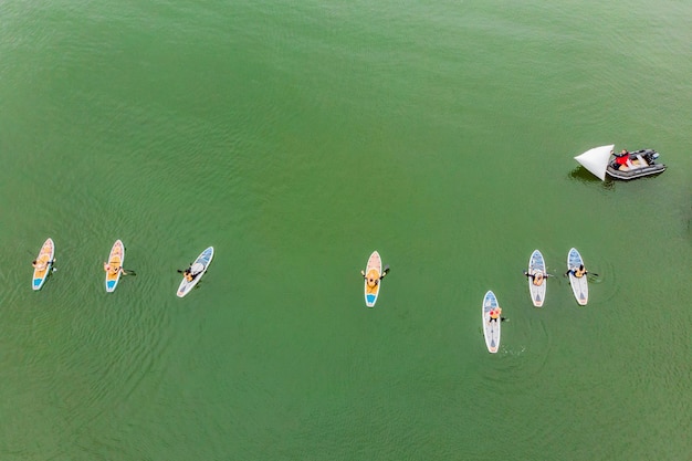 Starke Männer, die an einem sonnigen Tag auf einem SUP-Brett in einer wunderschönen Bucht schwimmen Luftaufnahme der Männer überquert die Bucht mit dem Paddleboard Wassersportwettbewerbe