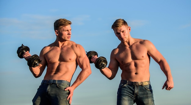 Starke und fitte Männerbodybuilder. Zwillinge muskulöse Männer. athletischer Mann sexy Körper. Sportliche muskulöse Jungs mit Langhantel und Kurzhanteln. Zwillinge trainieren zusammen. Muskelkraft und Kraft entwickeln.