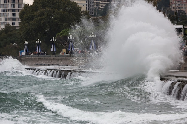 Starke Welle, die auf Küstenstadt bricht. Saisonaler Sturm an der Küste im Winter. Schlechtes stürmisches Wetter Saison