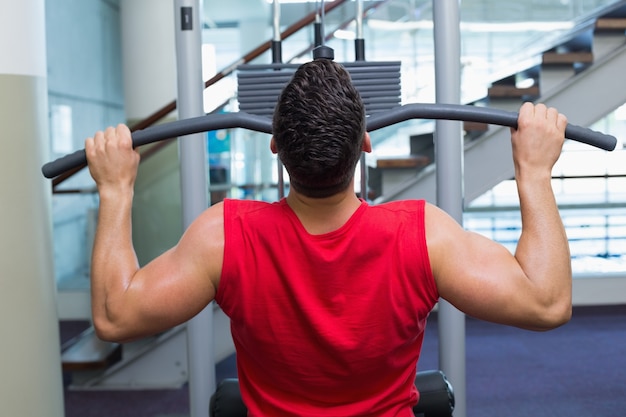 Starker Bodybuilder, der Gewichtsmaschine für Arme verwendet