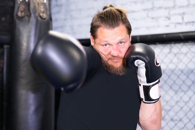 Starker ernsthafter Athlet boxt Boxtraining im Fitnessstudio in Handschuhen