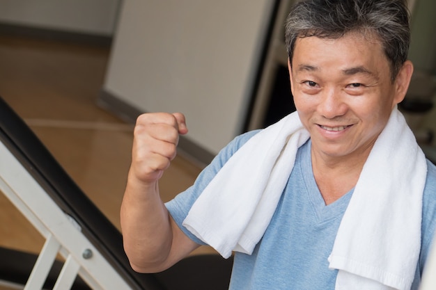 Starker, gesunder, glücklicher, lächelnder, positiver älterer asiatischer Mann, der im Fitnessstudio trainiert