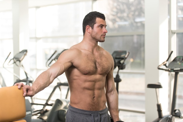 Starker haariger Mann im Fitnessstudio und Trainieren der Schultern mit Hanteln Muskulöser athletischer Bodybuilder Fitness Model Übungsschulter