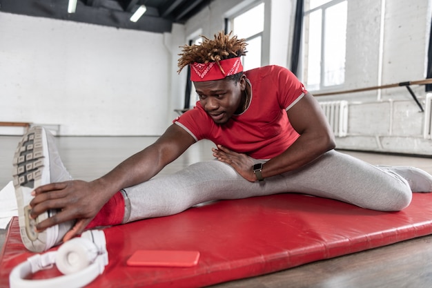 Starker hartnäckiger Mann, der sportliches Training hat, während er auf roter Matte liegt