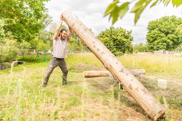 Starker Holzfäller, der mit bloßen Händen einen Baumstamm anhebt