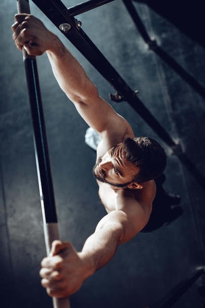 Starker junger muskulöser Mann, der im Fitnessstudio Klimmzüge macht.