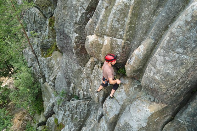 Starker männlicher Bergsteiger, der die steile Wand des felsigen Berges erklimmt Sportler, der schwierige Routen überwindet Engagement im Extremsport-Hobbykonzept