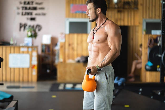 Starker Mann, der mit einer Kettlebell in einem Fitnessstudio steht