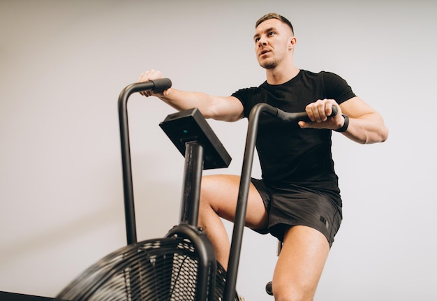 Starker Mann mit Air Bike für Cardio-Training im Cross-Trainings-Fitnessstudio