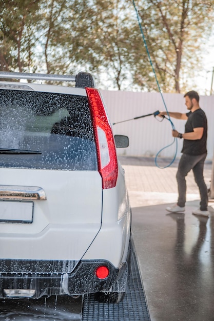 Foto starker mann wäscht auto bei selbstwäsche im freien