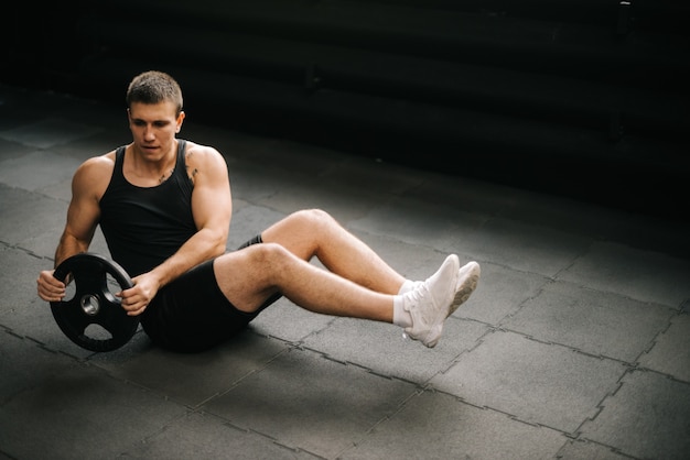 Starker muskulöser fitter Mann, der russische Drehübungen mit Gewicht von der Langhantel macht