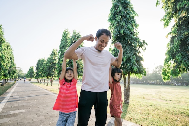 Starker Papa mit Kindern, die beim Training am Arm hängen