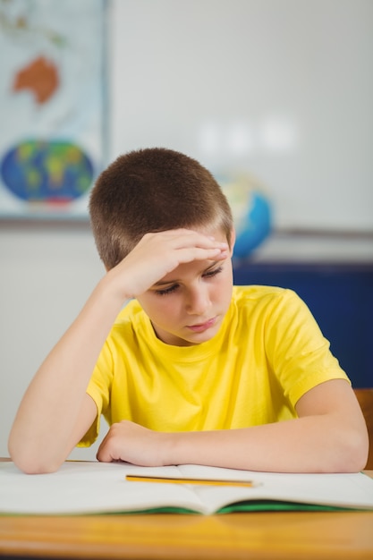 Starker Schüler, der an seinem Schreibtisch in einem Klassenzimmer arbeitet