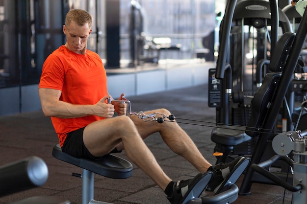 Starker Sportler, der Muskeln im Fitnessstudio aufpumpt. Muskel-Typ-Training. Übungen für Presse, Bizeps, Beine.