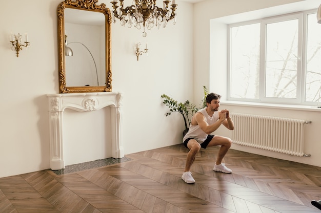 Starker, sportlich fitter Mann in T-Shirt und Shorts macht zu Hause in seinem geräumigen und geräumigen ...