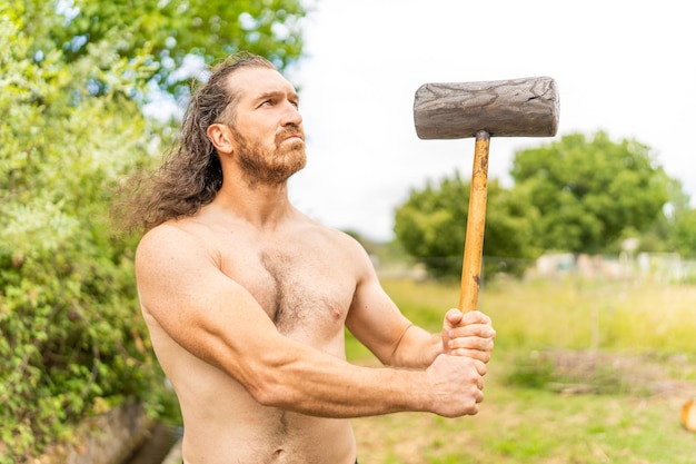 Starker wilder Mann mit einem Hammer, der oben schaut