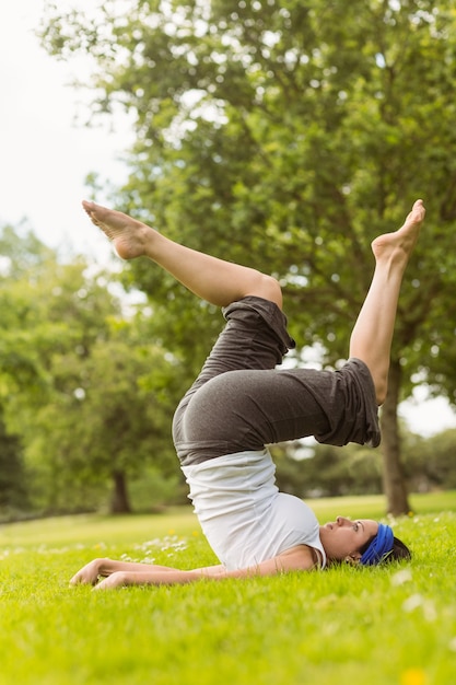 Starkes braunes Haar, das Yoga auf Gras tut