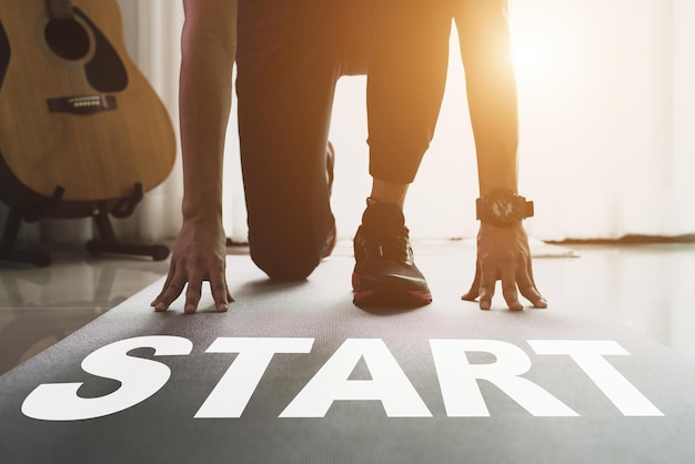 Starten Sie gerade Konzept Word Start geschrieben auf der schwarzen Yogamatte und junger Athlet auf Yogamatte, der morgens zu Hause Übungen macht Er war bereit, etwas Neues zu beginnen