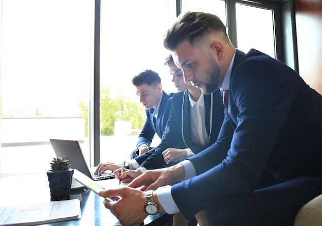 Startup-Business-Team bei Treffen in modernen, hellen Büroräumen, Brainstorming, Arbeiten an Laptop und Tablet-Computer