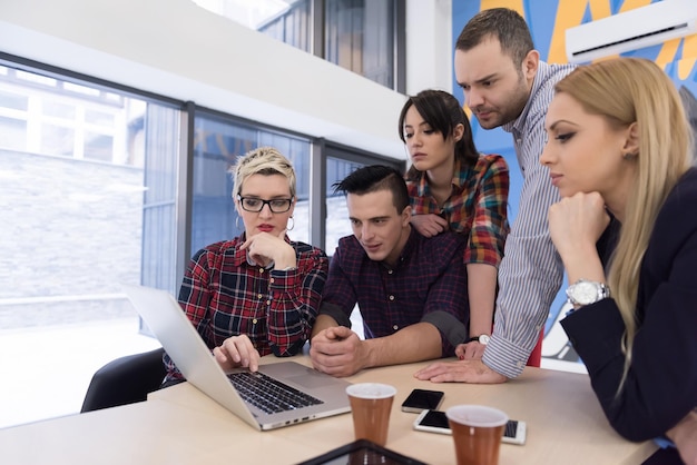 Startup-Business-Team bei Treffen in modernen, hellen Büroräumen, Brainstorming, Arbeiten an Laptop und Tablet-Computer