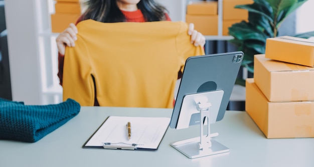 Startup PME pequeno empresário de freelance mulher asiática usando um laptop com caixa sucesso alegre mulher asiática sua mão levanta caixa de embalagem de marketing on-line e entrega conceito de ideia de PME