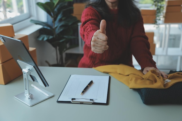 Startup PYME emprendedora de pequeñas empresas de una mujer asiática independiente usando una computadora portátil con caja Éxito alegre Mujer asiática su mano levanta la caja de embalaje de marketing en línea y el concepto de idea de PYME de entrega