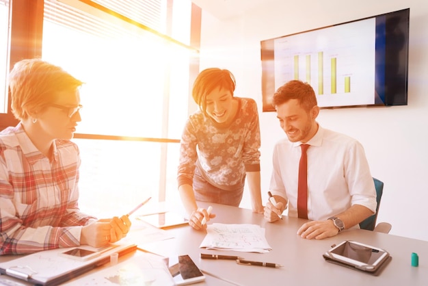 Startup-Unternehmen junge kreative Menschen gruppieren Brainstorming bei Treffen im Büro mit Laptop und Tablet-Computer, um Ideenpläne und Projekte zu notieren Sonnenaufgang oder Sonnenuntergang mit Sonneneruption im Hintergrund