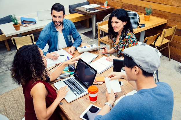 Startup von vier multiethnischen Menschen, die freudig Ideen in einem modernen Coworking-Espace diskutieren