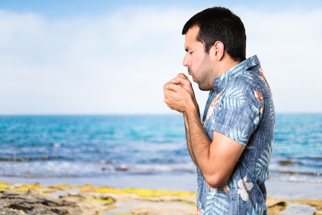 Stattlicher Mann mit Blumenhemd hustet viel am Strand