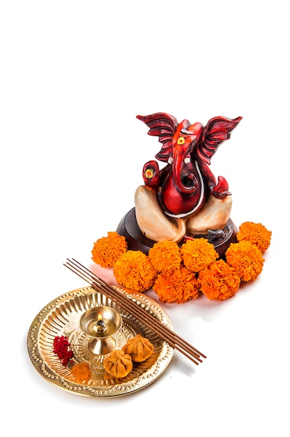 Statue des hinduistischen Gottes Ganesha mit Anbetungsanordnung auf weißer Oberfläche.