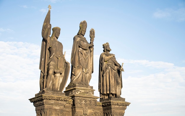 Statue von drei Heiligen auf der Karlsbrücke in Prag von vorne am Tag des blauen Himmels