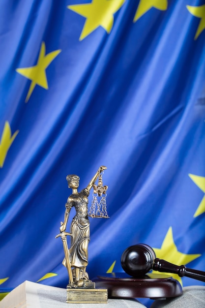 Statue von Themis auf einer Flagge der Europäischen Union. Richterhammer im Hintergrund