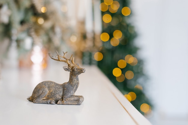 Statuette eines Hirsches auf dem Hintergrund der Weihnachtsbeleuchtung. Neujahrskarte mit Kopierplatz