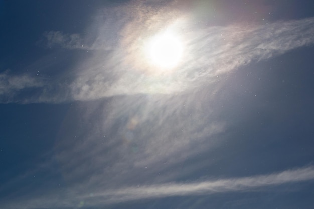 Staubpartikel am blauen Himmel mit Sonne und Federwolke am Frühlingstag