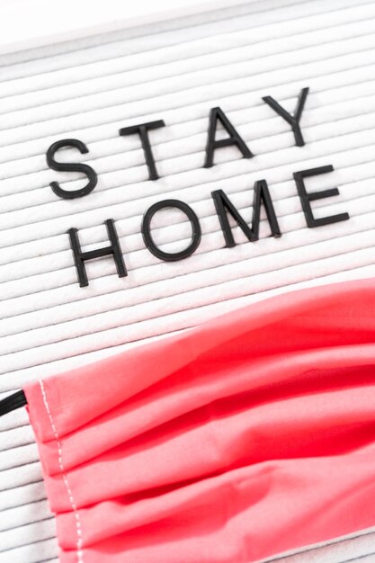 STAY HOME-Schild auf dem Message Board mit einer hausgemachten Gesichtsmaske