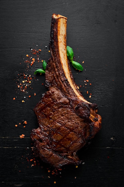 Steak auf dem Knochen Tomahawk-Steak auf schwarzem Holzhintergrund Draufsicht Freier Kopierbereich