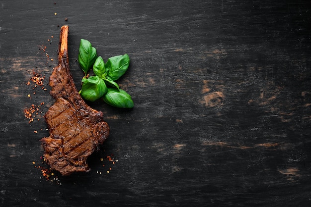 Steak auf dem Knochen Tomahawk-Steak auf schwarzem Holzhintergrund Draufsicht Freier Kopierbereich