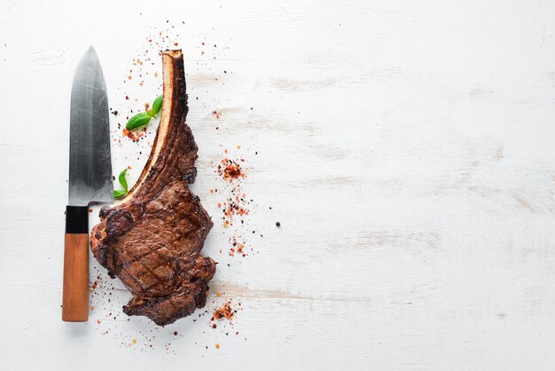 Steak auf dem Knochen-Tomahawk-Steak auf weißem Holzhintergrund Draufsicht Freier Kopierbereich