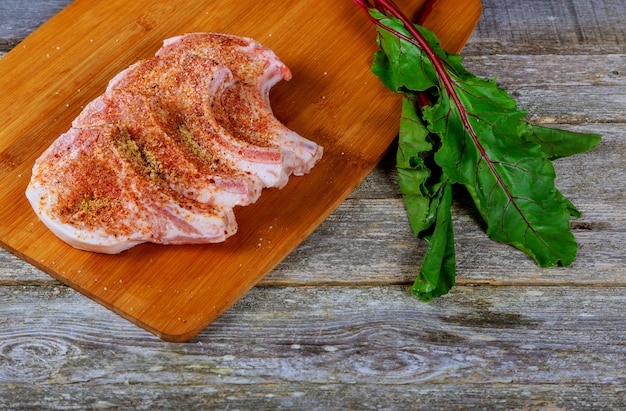 Steak des rohen Fleisches auf dunklem hölzernem Brett.