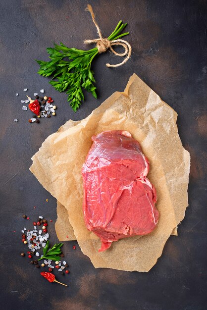 Steak des rohen Fleisches mit Gewürzen auf rostigem Hintergrund