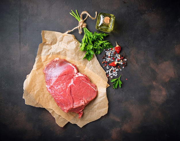 Steak des rohen Fleisches mit Gewürzen auf rostigem Hintergrund