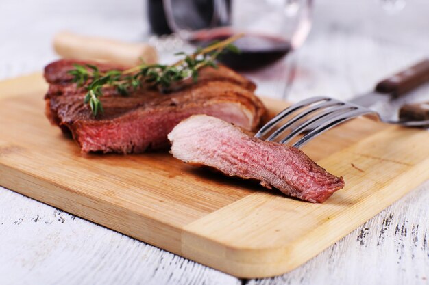 Steak mit Kräutern auf Holzständer und Wein auf dem Tisch aus nächster Nähe