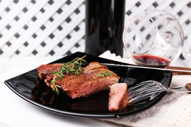 Steak mit Kräutern auf Teller mit Wein auf Holzhintergrund