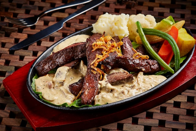 Steak mit Kräutersauce, schickes Rindfleisch, serviert in Gerichten, die auf dem Tisch isoliert sind, Seitenansicht von Speisen aus dem Nahen Osten