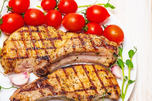 Steak mit Tomaten grünen Knoblauch auf einem weißen Teller auf dem Tisch Foto von Fleisch